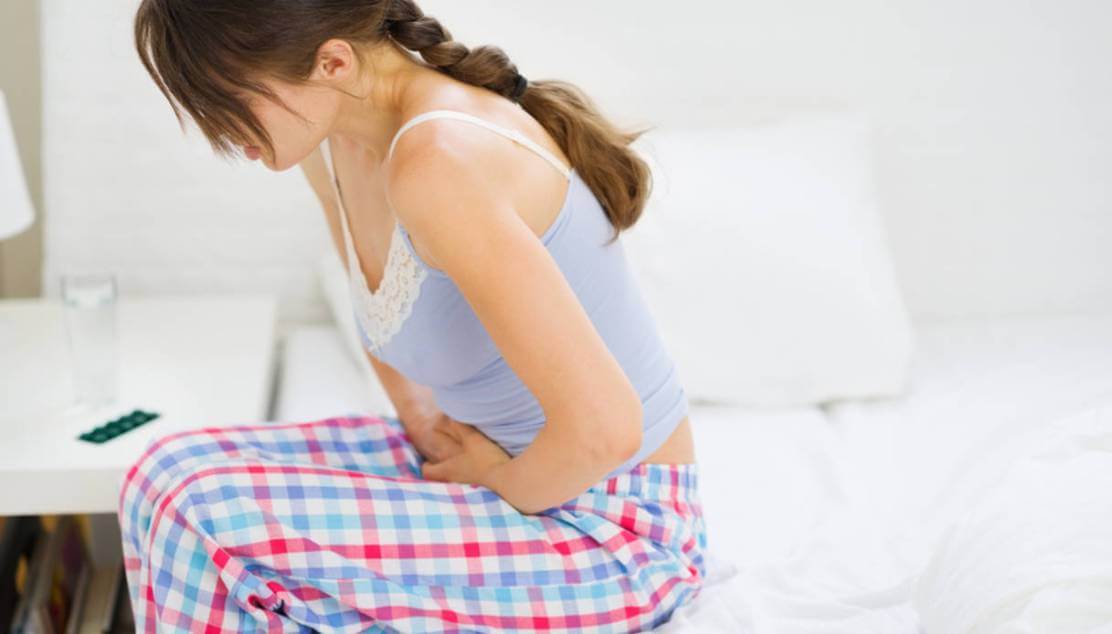 Girl with stomach ache sitting on bed Dolori mestruali o dismenorrea 4 tisane per alleviare il dolore immediatamente
